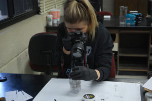 Kylee Morrison taking photographs of fingerprints from a piece of evidence