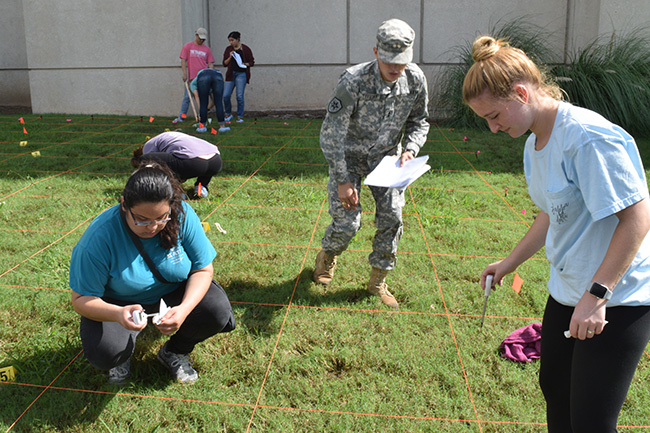 Students survey a section of ground at a mock crime scene. Photo by Rob Williams.