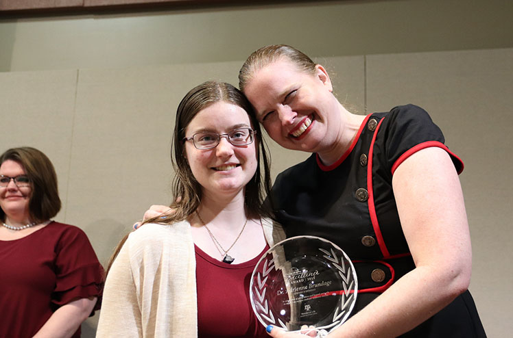 Adrienne and a student standing together with Adrienne's award
