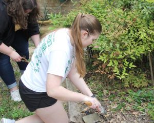 Raven Johnson, left, and Brittany Gerich, right, clean out a flowerbed at a residence in Bryan. Photo by Rob Williams