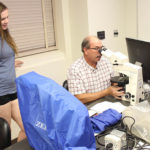 Scott Kovar, right, showing Rachel McNeal how to calibrate the microscope during the lab. Photo by Rob Williams.